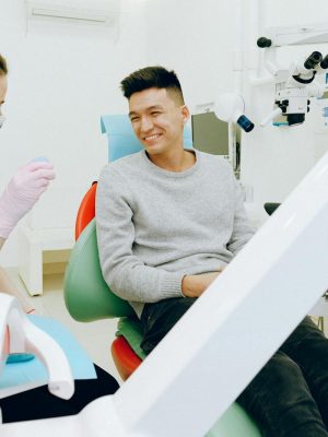 A dentist and patient smiling during a dental checkup, showcasing friendly healthcare interaction indoors.