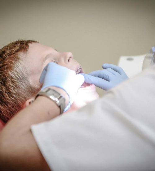 A young boy receiving a dental examination by a professional dentist in a clinic setting.